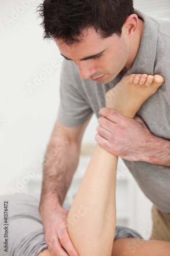 Physiotherapist manipulating the leg of a woman while she is lyi