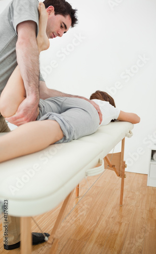 Serious physiotherapist stretching the leg of a woman