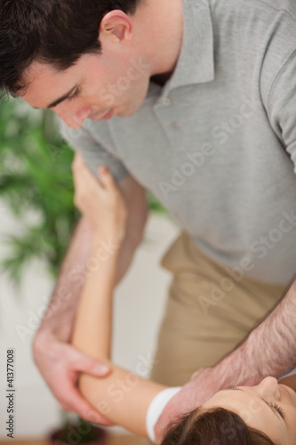 Physiotherapist holding the arm and the shoulder of a patient