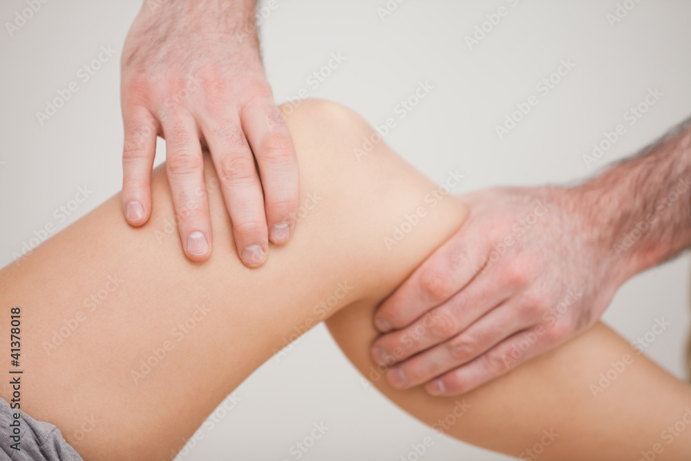 Knee of a patient being touched by a practitioner Knee of a patient being touched by a practitioner