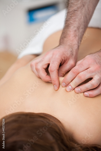 Back of a woman being massaging while fingertips of doctor