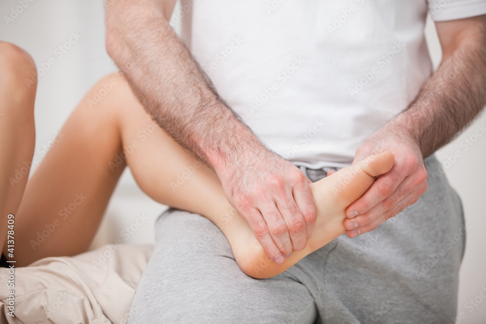 Reflexologist manipulating the foot of his patient while holding Reflexologist manipulating the foot of his patient while holding