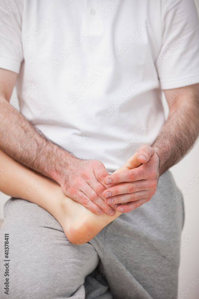 Podiatrist manipulating the foot of a woman while holding it on Podiatrist manipulating the foot of a woman while holding it on