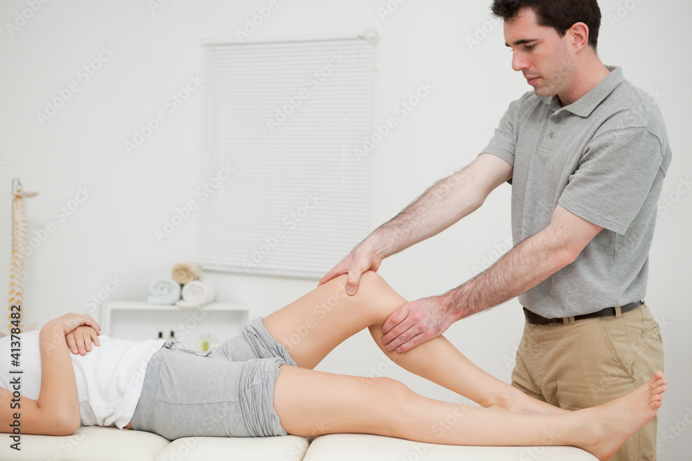 Physiotherapist examining the knee of his patient while touching Physiotherapist examining the knee of his patient while touching