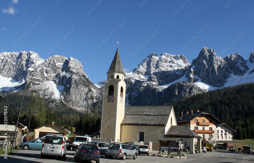 Bell Tower of a church and the background of the Dolomites in Ca