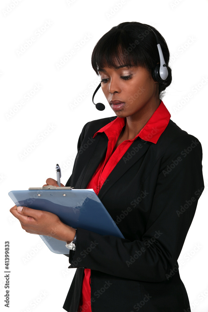 Woman wearing a headset and writing on a clipboard Woman wearing a headset and writing on a clipboard