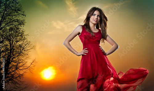 lady in red and colorful sky behind