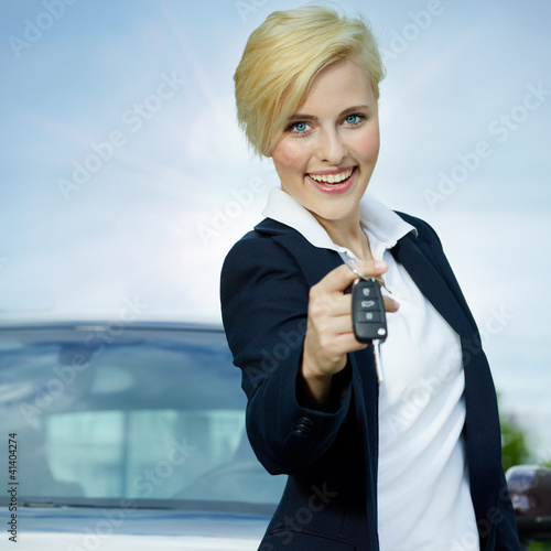 Pretty blonde woman proudly presents the key of her car photo