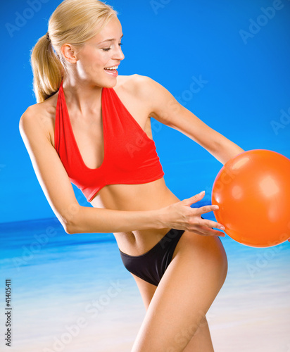 Young woman playing with ball on beach