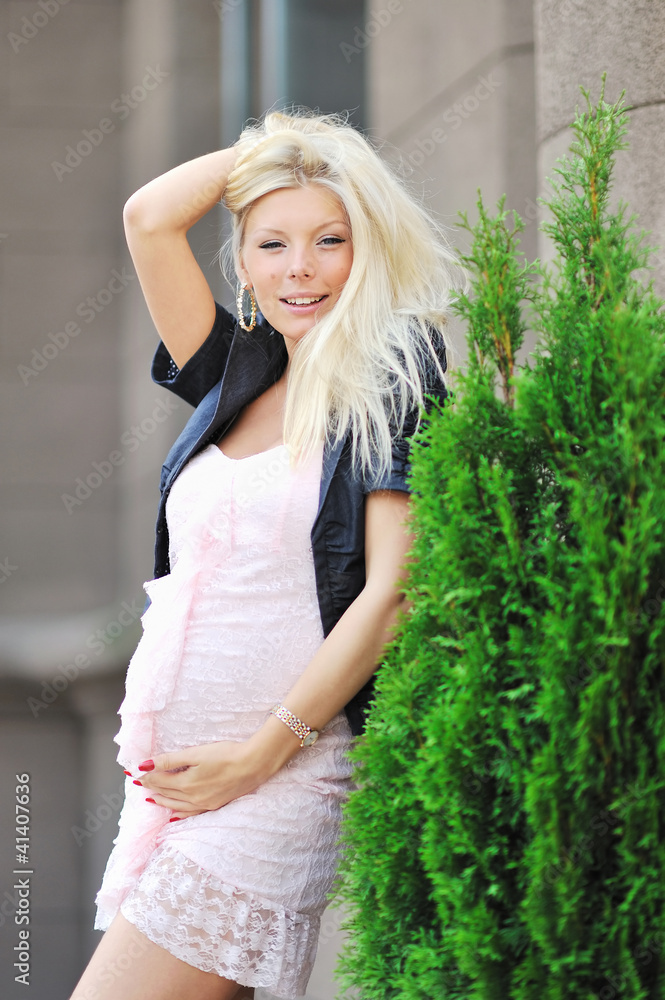 Obraz premium Pretty pregnant girl touching her tummy and posing outdoors