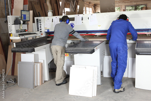 Two factory workers operating saw photo