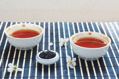 Two cups of tea, jar of tea leaves and cherry blossoms photo