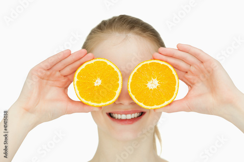 Close up of a smiling woman placing oranges on her eyes