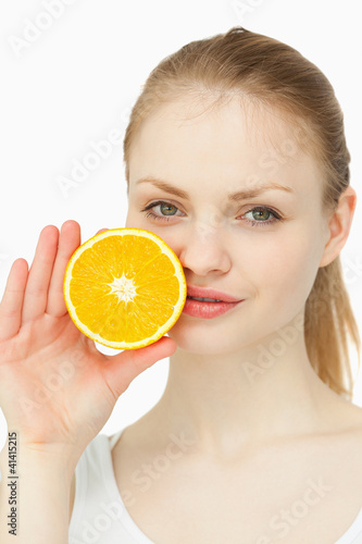 Woman placing an orange on her lips