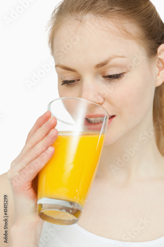 Woman drinking a glass of orange juice while looking at it