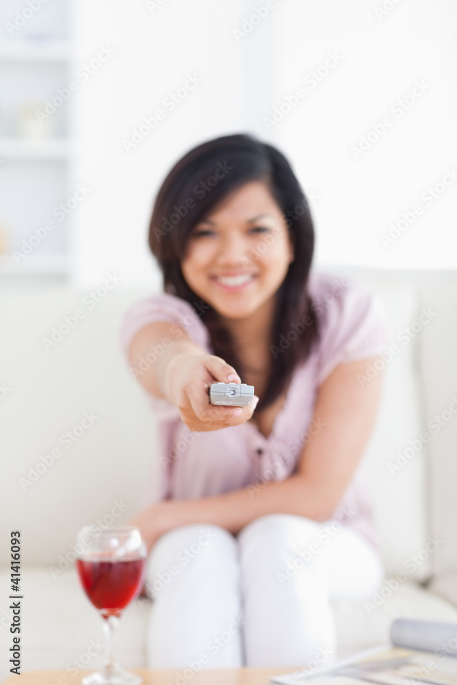 Blurred woman holding a television remote while sitting on a cou Blurred woman holding a television remote while sitting on a cou