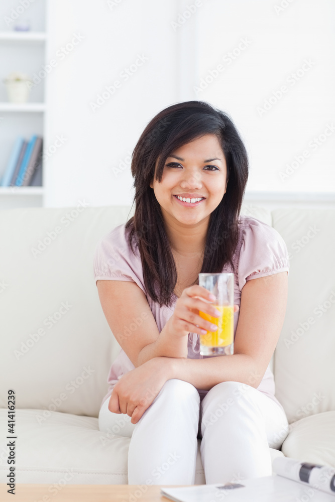 Smiling woman sitting and holding a glass of orange juice Smiling woman sitting and holding a glass of orange juice