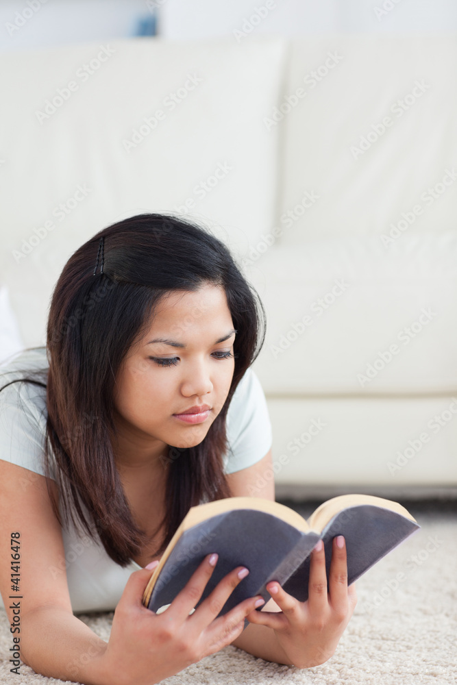 Woman laying on the floor while reading a book Woman laying on the floor while reading a book
