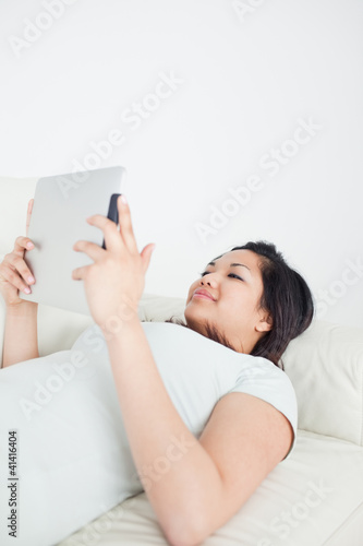 Woman lying on a sofa while holding a tactile tablet
