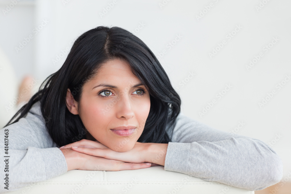 Woman crossing her arms under her head on a sofa Woman crossing her arms under her head on a sofa