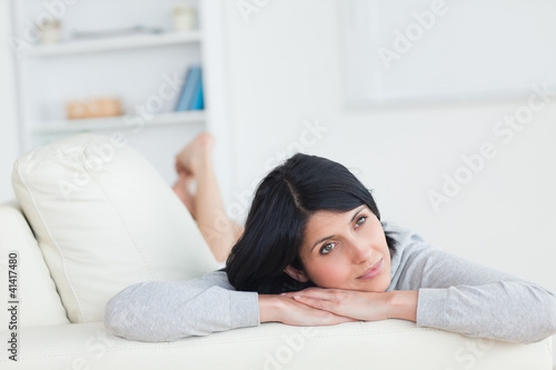Woman laying on a sofa while holding up her head