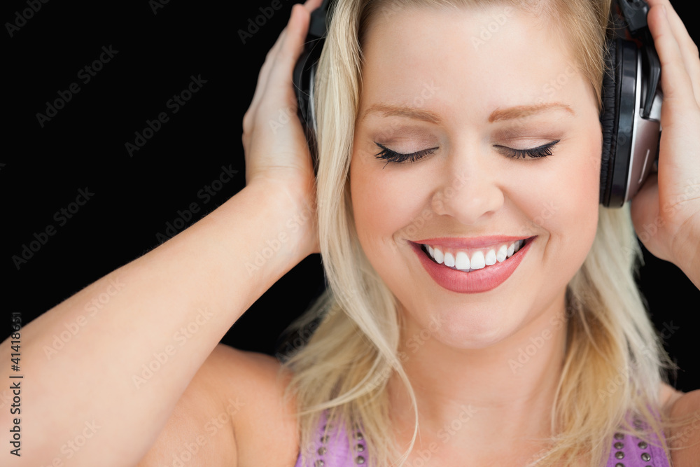 Smiling blonde woman wearing her headphones Smiling blonde woman wearing her headphones