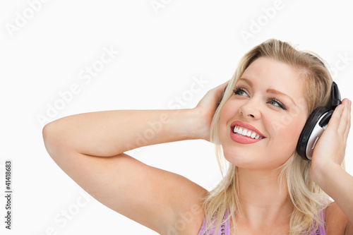 Smiling blonde woman looking up while listening to music