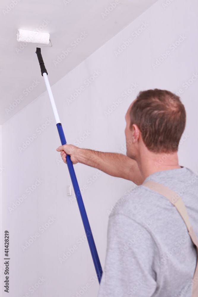 Decorator painting a ceiling white Decorator painting a ceiling white