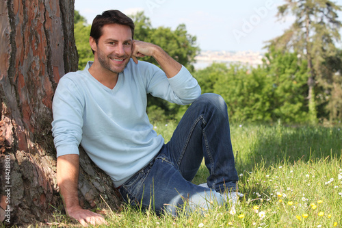 Man sitting against tree