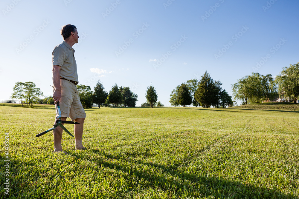 Senior man cutting grass with shears Senior man cutting grass with shears
