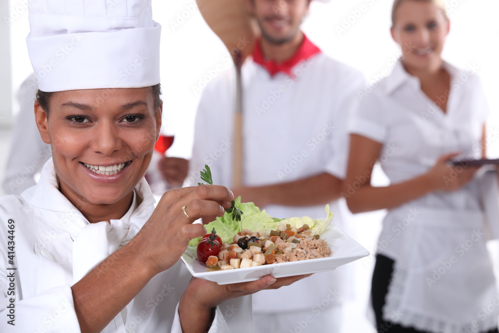 a cook holding a dish, a pizza cook and a waitress a cook holding a dish, a pizza cook and a waitress