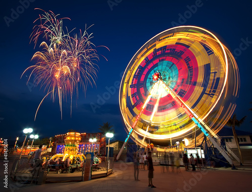 Amusement park at night - ferris wheel  in motion and firework