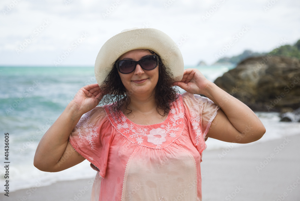 A woman in a white hat and sunglasses on the beach