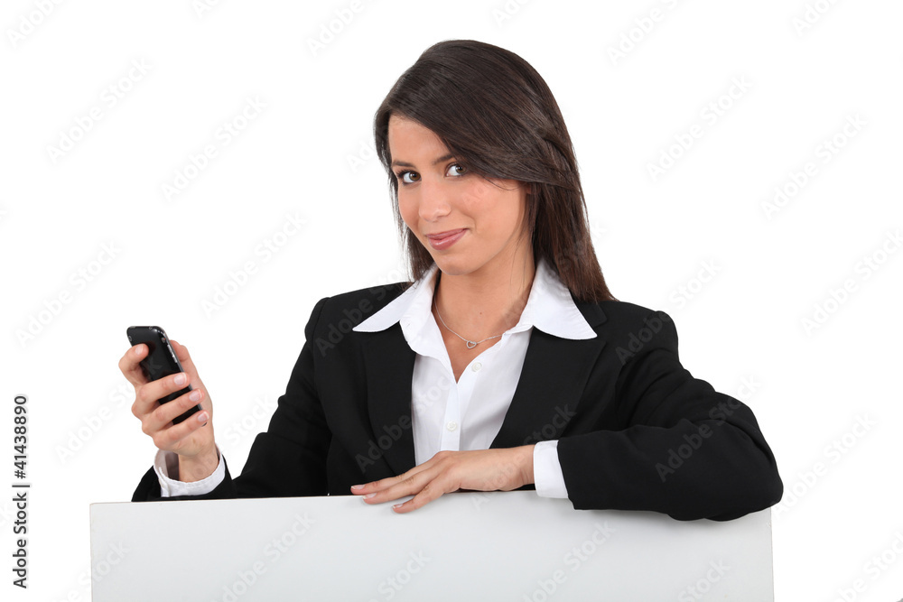 Businesswoman with mobile posing by blank poster Businesswoman with mobile posing by blank poster