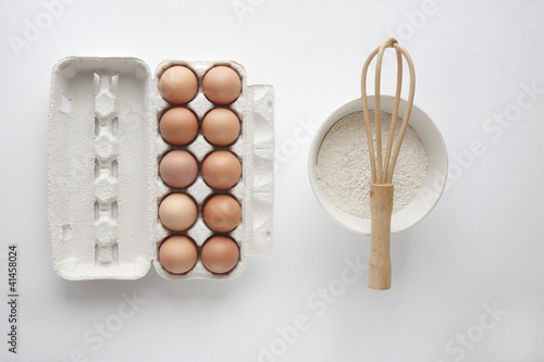 Flour in bowl with eggs on white background