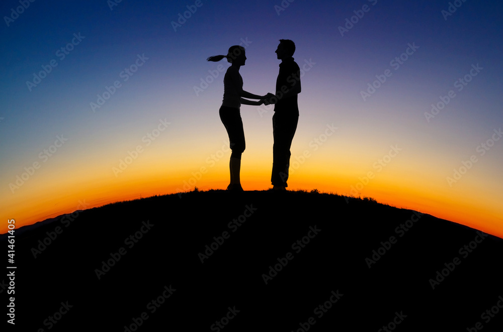 silhouette of couple on hill in sunset