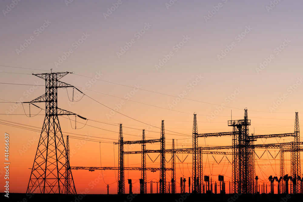 Fototapeta premium Silhouetted power pylons against a red sky at sunset