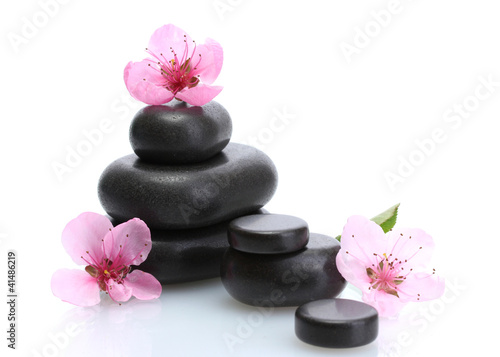 Spa stones and pink sakura flowers isolated on white.