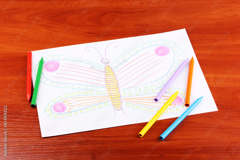 Children's drawing of butterfly and pencils on wooden background Children's drawing of butterfly and pencils on wooden background