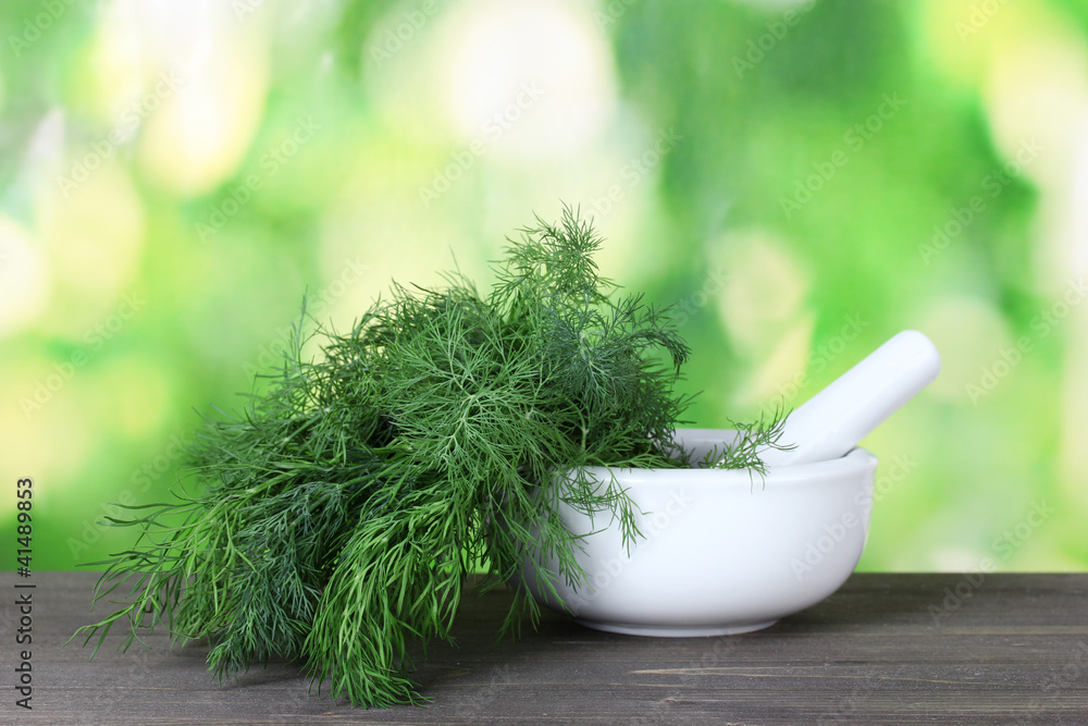 Dill in a mortar and pestle on green background