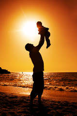 father and daughter playing on the beach at sunset