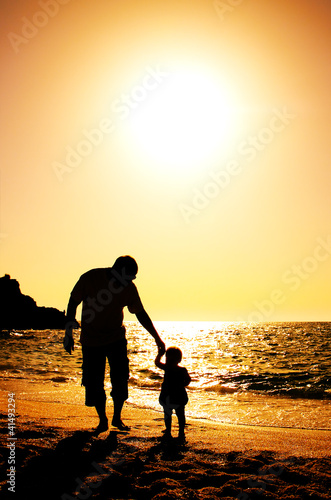 father and daughter playing on the beach at sunset