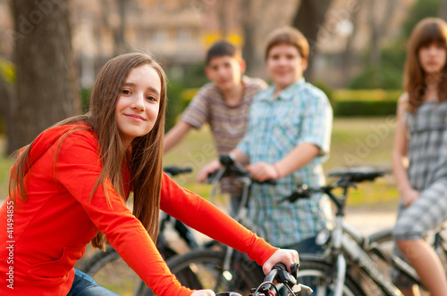 Beautiful teenage girl with her friends riding bicycles