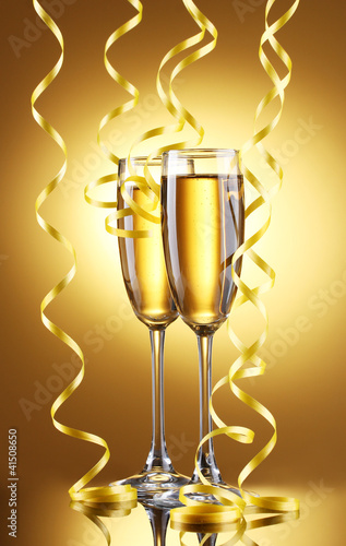 glasses of champagne and streamer on yellow background photo