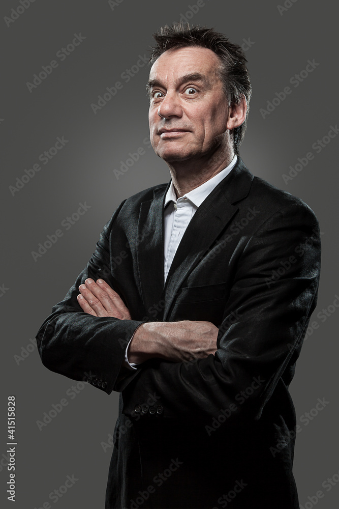 Handsome Middle Age Business Arms Folded Pulling Face on Grey