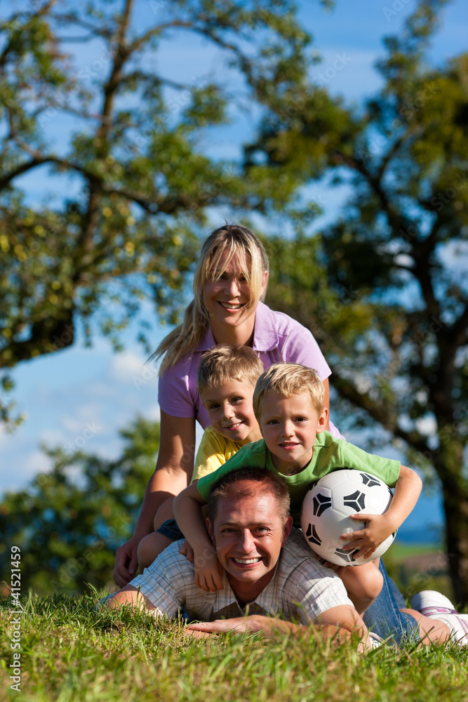 Fototapeta premium Familie mit Kindern und Fußball auf einer Wiese