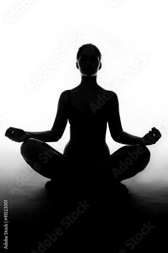 Silhouette of woman sitting in lotus position