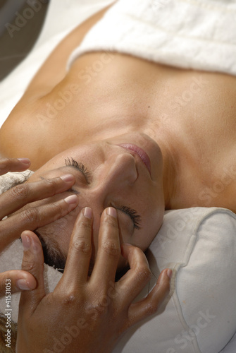 Joven mujer recibiendo un masaje facial en un spa.