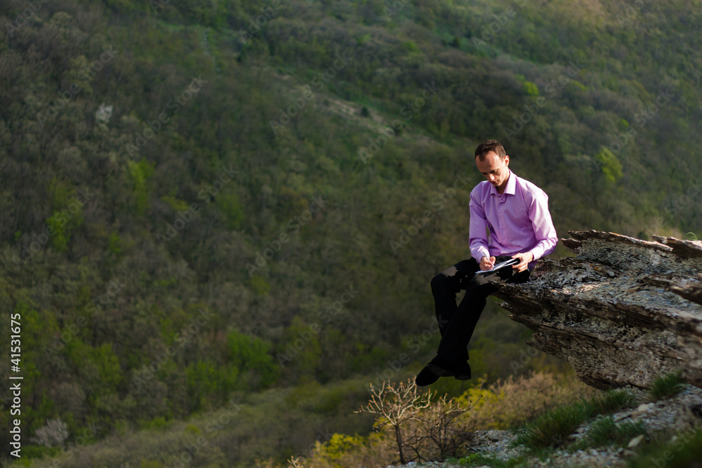 man with notepad on stone