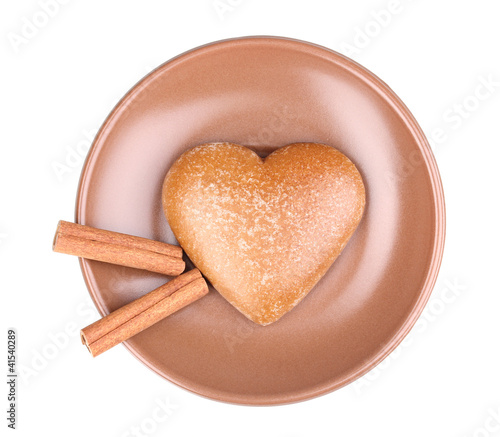 Heart-shaped cookie with cinnamon on saucer isolated on white